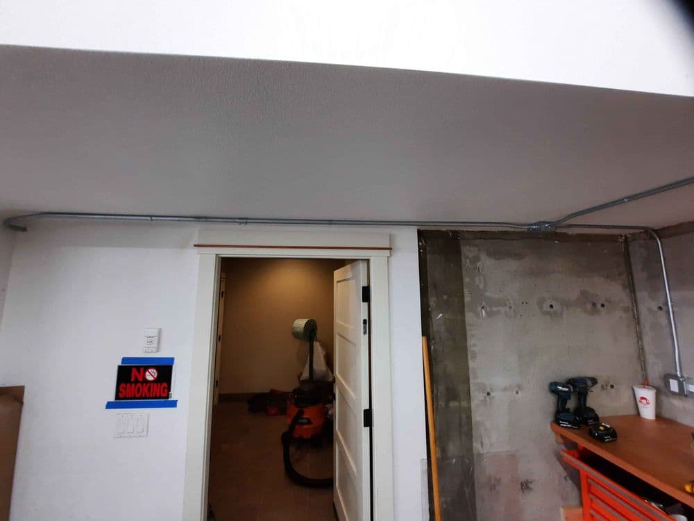 Interior view of a basement with visible door, vacuum cleaner, and "No Smoking" sign.