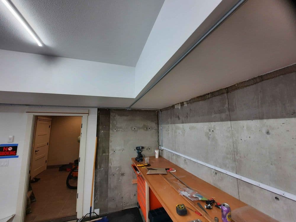 Interior of a garage with a clean workspace, concrete walls, and tools on a bench.