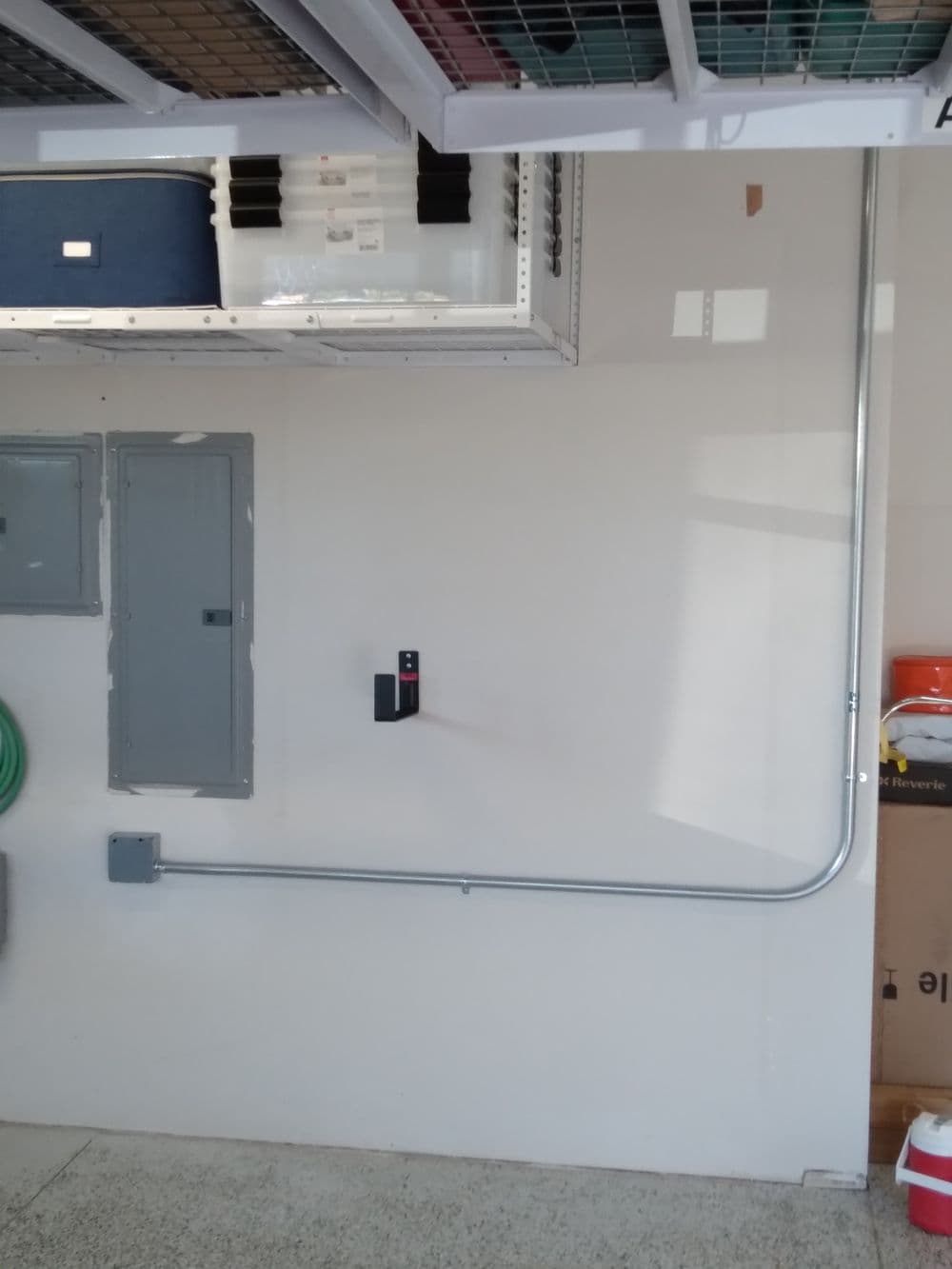 Garage wall with electrical panel, conduit, and storage boxes. Organized and functional space.