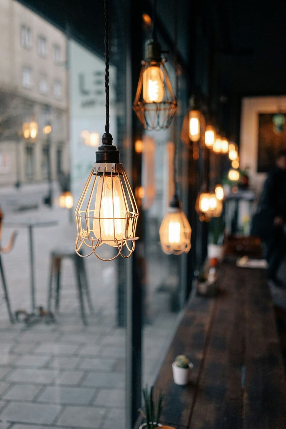 Vintage pendant lights hanging in a stylish café with wooden tables and a cozy atmosphere.