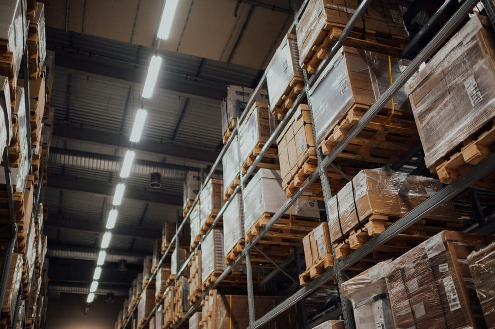 Warehouse shelves stacked with pallets of packaged goods under bright lighting.