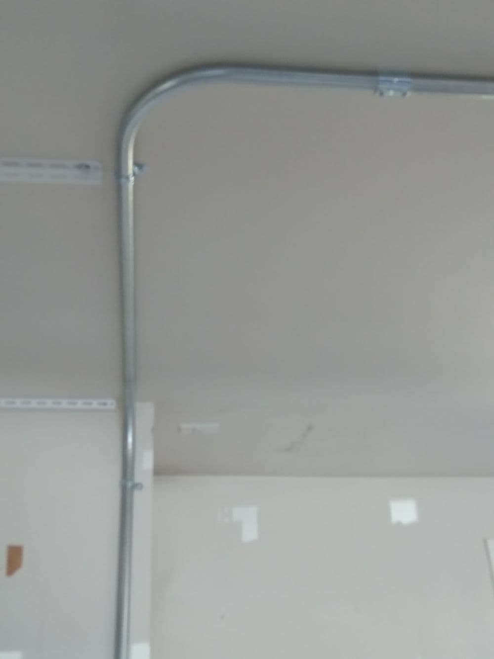 Ceiling-mounted metal conduit bending at an angle, secured with brackets.