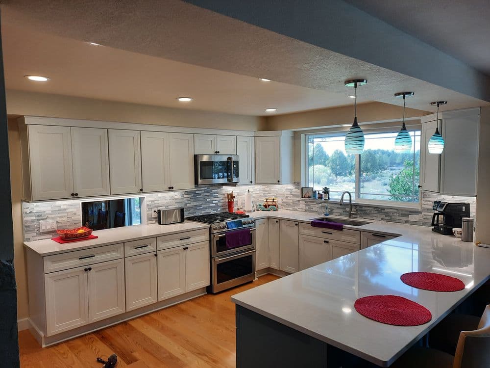 Modern kitchen with white cabinets, stainless steel appliances, and stylish blue pendant lights.