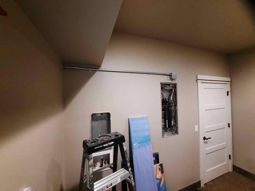 Interior room under construction with a ladder, wall-mounted electrical panel, and plumbing.