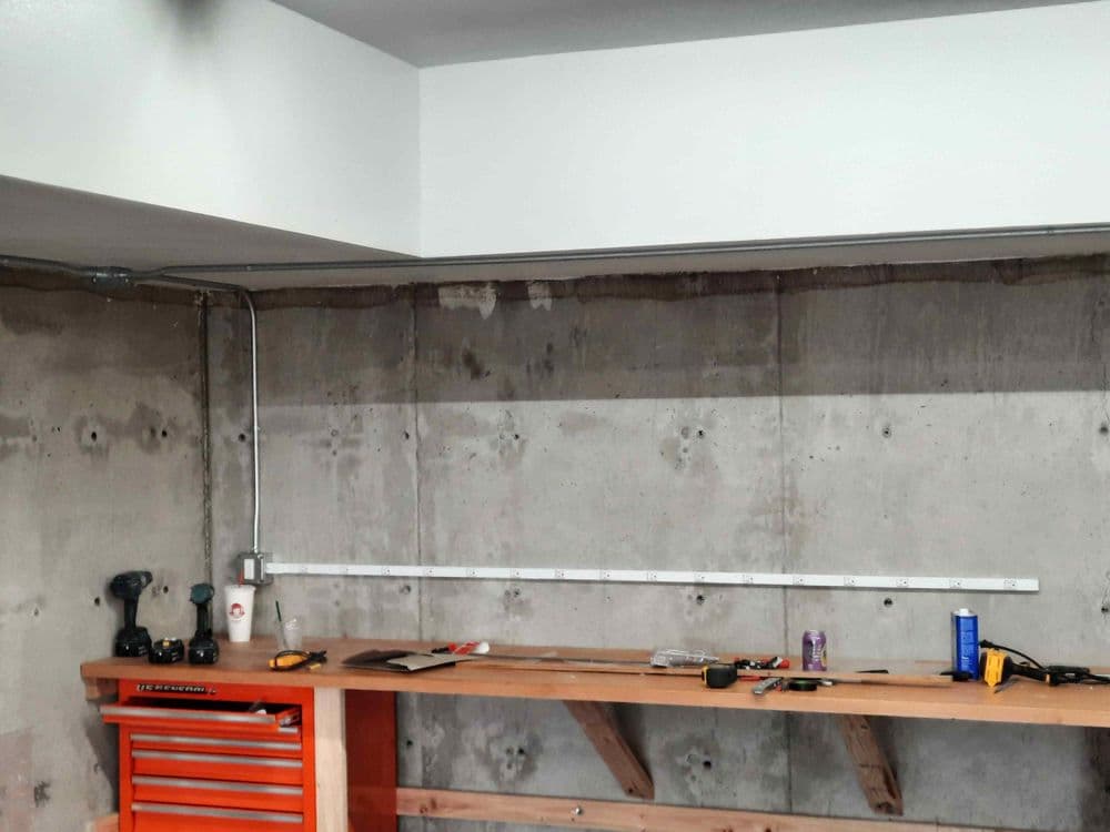 Home workshop with concrete wall, wooden workbench, and tools organized on a red toolbox.