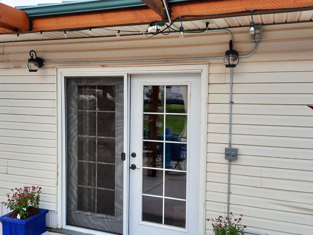 Patio entrance with double glass doors, wall lights, and blue planter beneath.