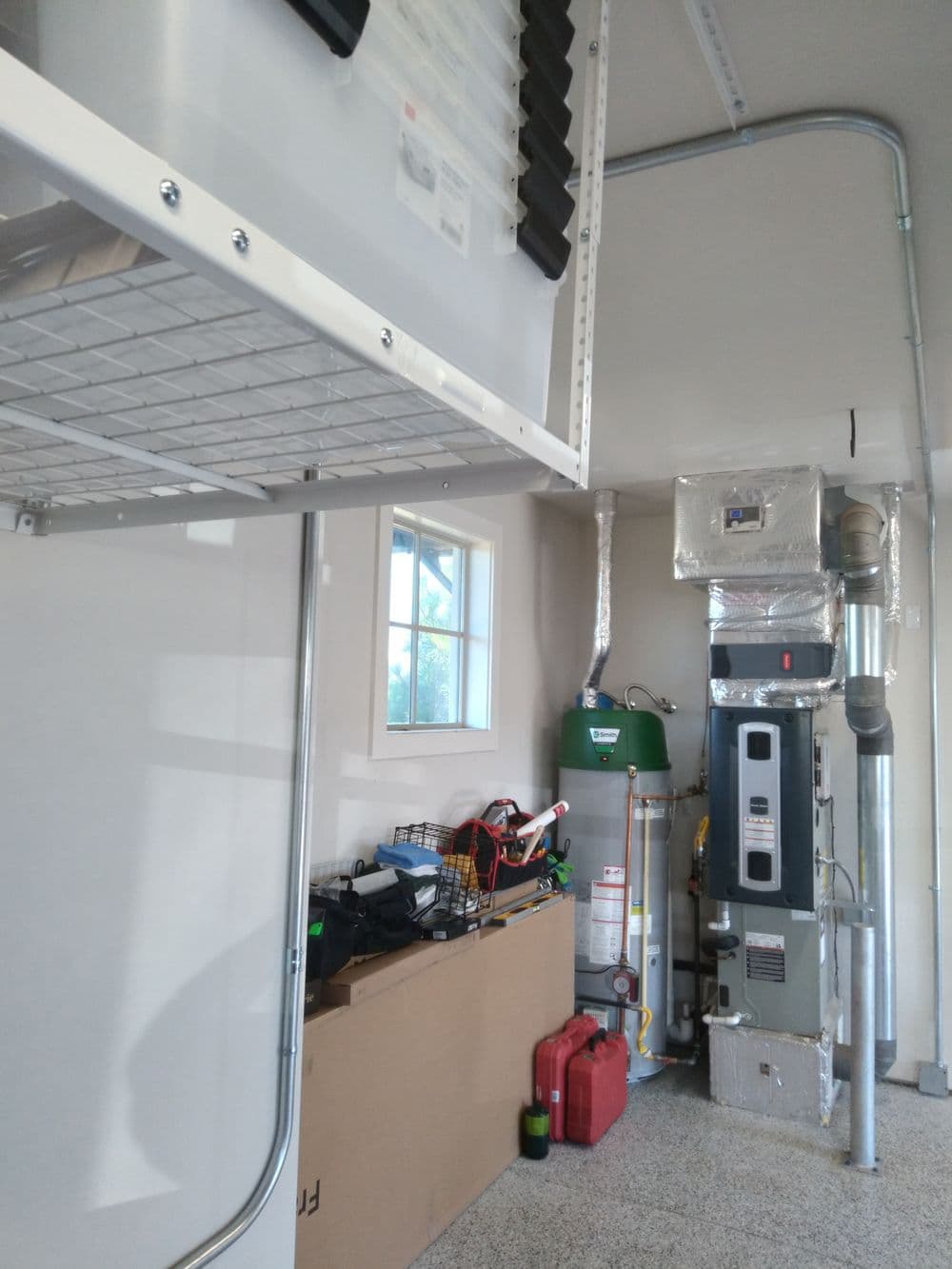 Garage interior featuring storage shelves, water heater, and furnace. Organized space for equipment.