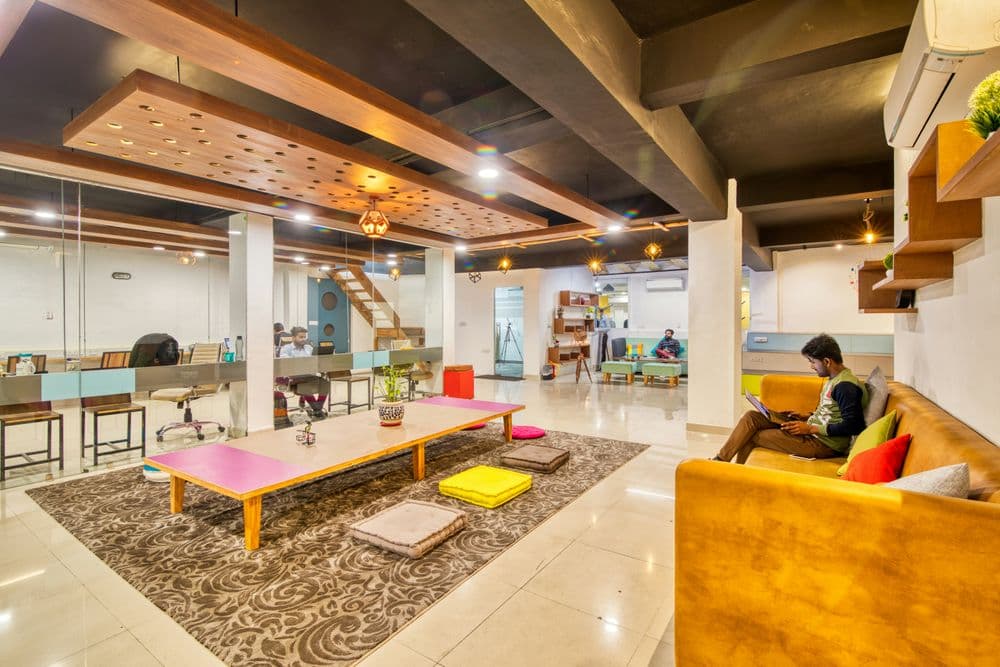 Modern co-working space with stylish furniture, colorful rugs, and collaborative areas.